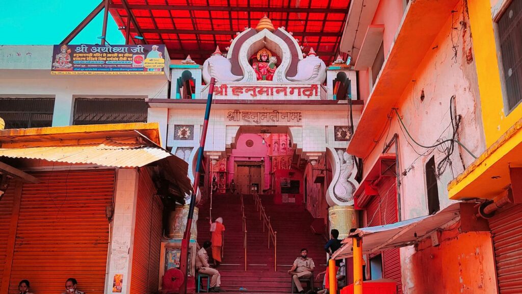 The entrance to the Hanuman Garhi temple in Nainital, featuring a colorful archway, a large staircase, and a crowd of people.